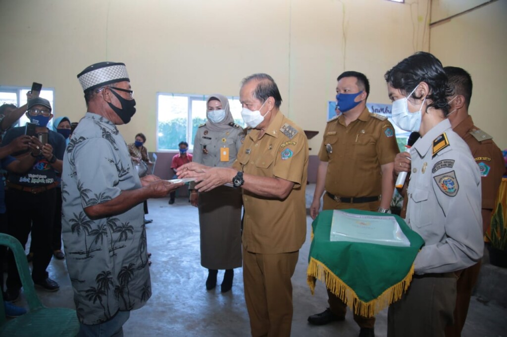 Wali Kota Bitung, Max J Lomban, menyerahkan sertifikat kepada perwakilan penerima, Senin (21/9) di Aula Kelurahan Wangurer Barat, Kecamatan Madidir.